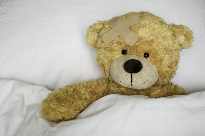 teddy bear with bandage on its head in bed