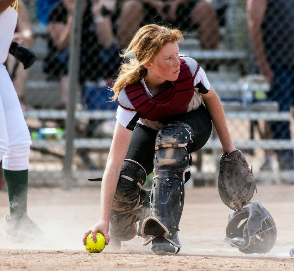 softball catcher in softball grabs ball