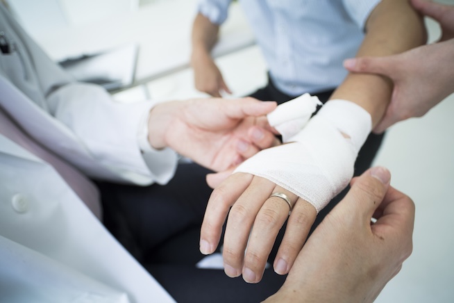 Medical provider wrapping bandage around patient's hand and wrist