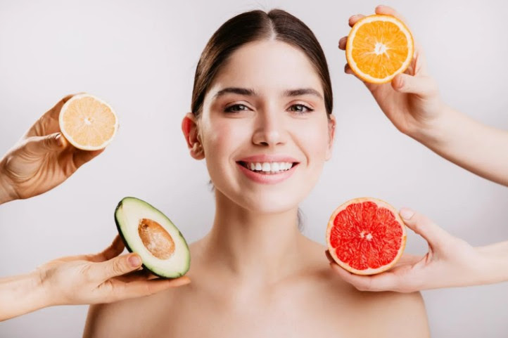 skinnutrition hands hold different fruit around a woman's face
