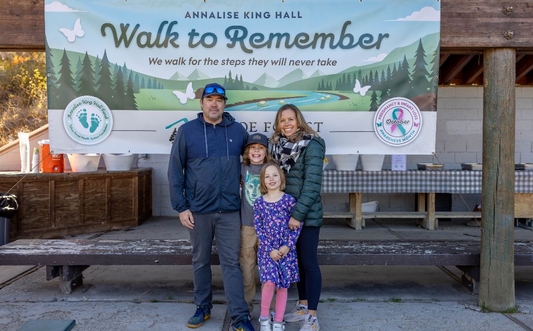 Family of four posing in front of the Walk to Remember banner at the pavilion