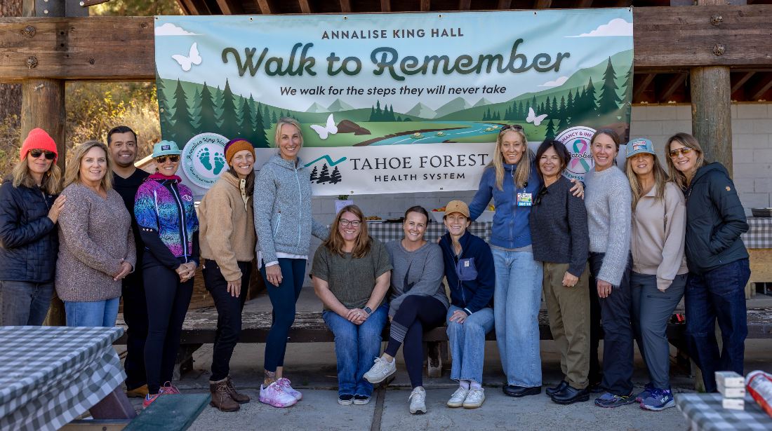 Group of participants posed together in front of the Walk to Remember banner