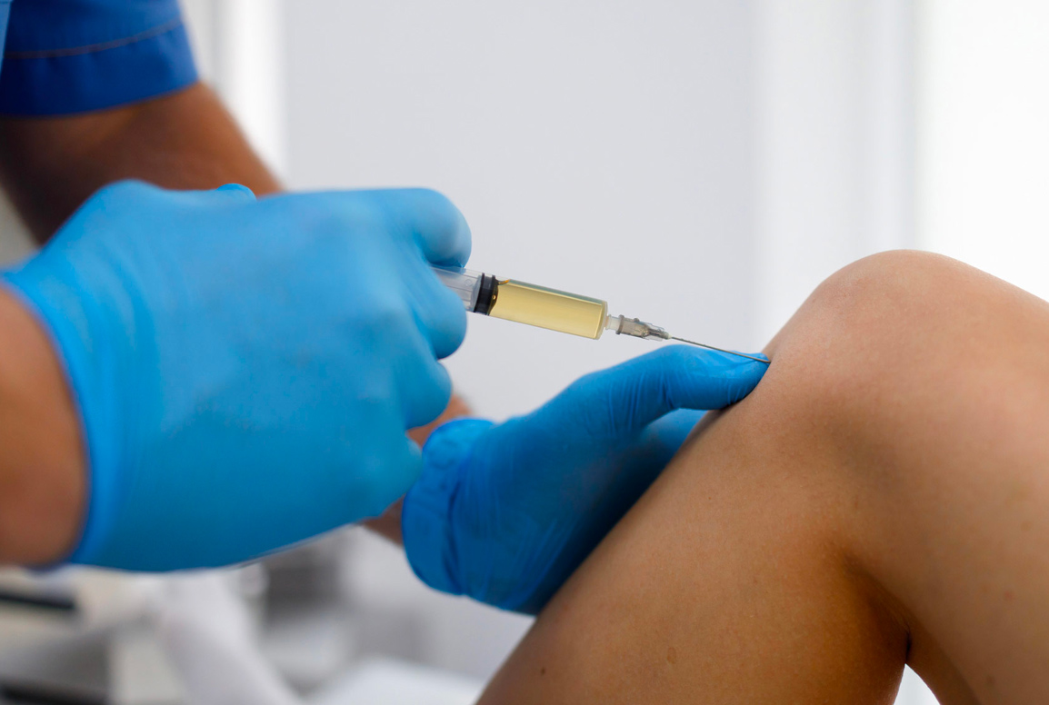 Injection Healthcare provider administering an injection to a patient’s knee