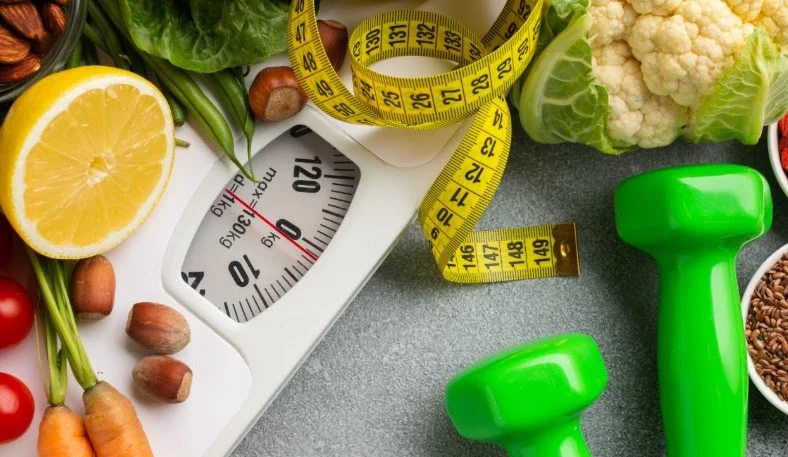 scale, measuring tape and weights arranged with vegetables