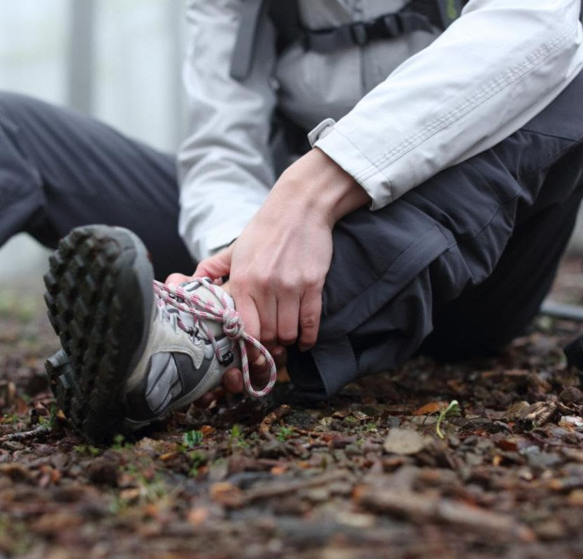 person holds ankle while sitting on the ground